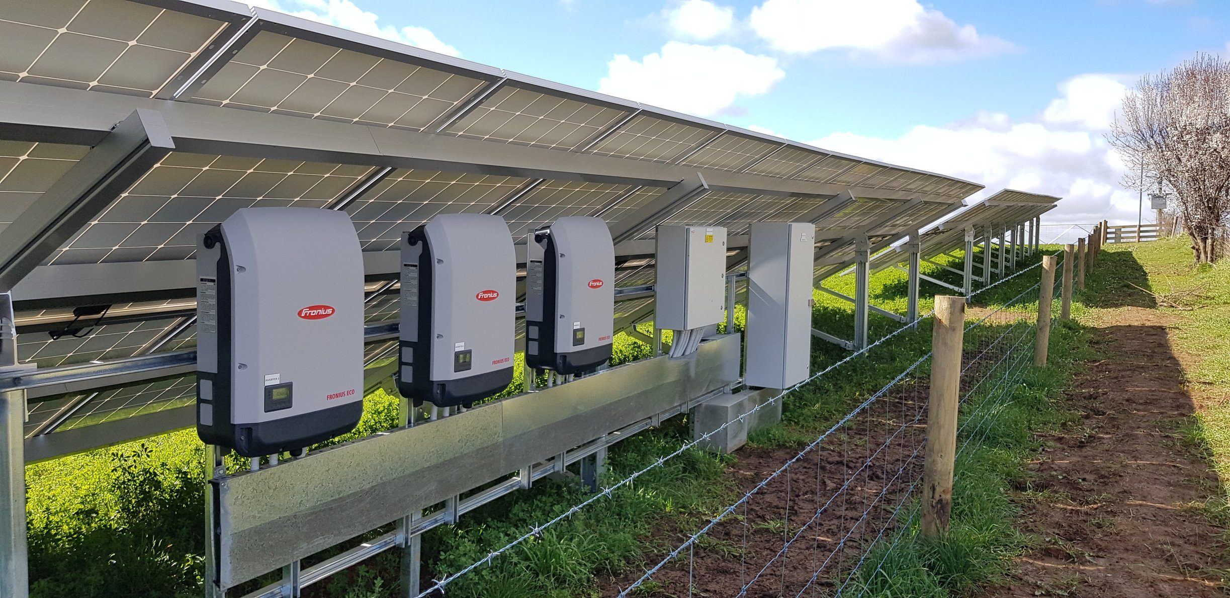 Three Fronius inverters wired up beneath a ground-mount solar array on a Tasmanian farm